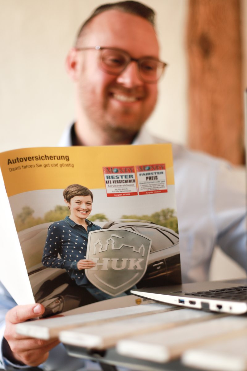 Sebastian Prillwitz mit einer HUK-COBURG Broschüre zur Autoversicherung